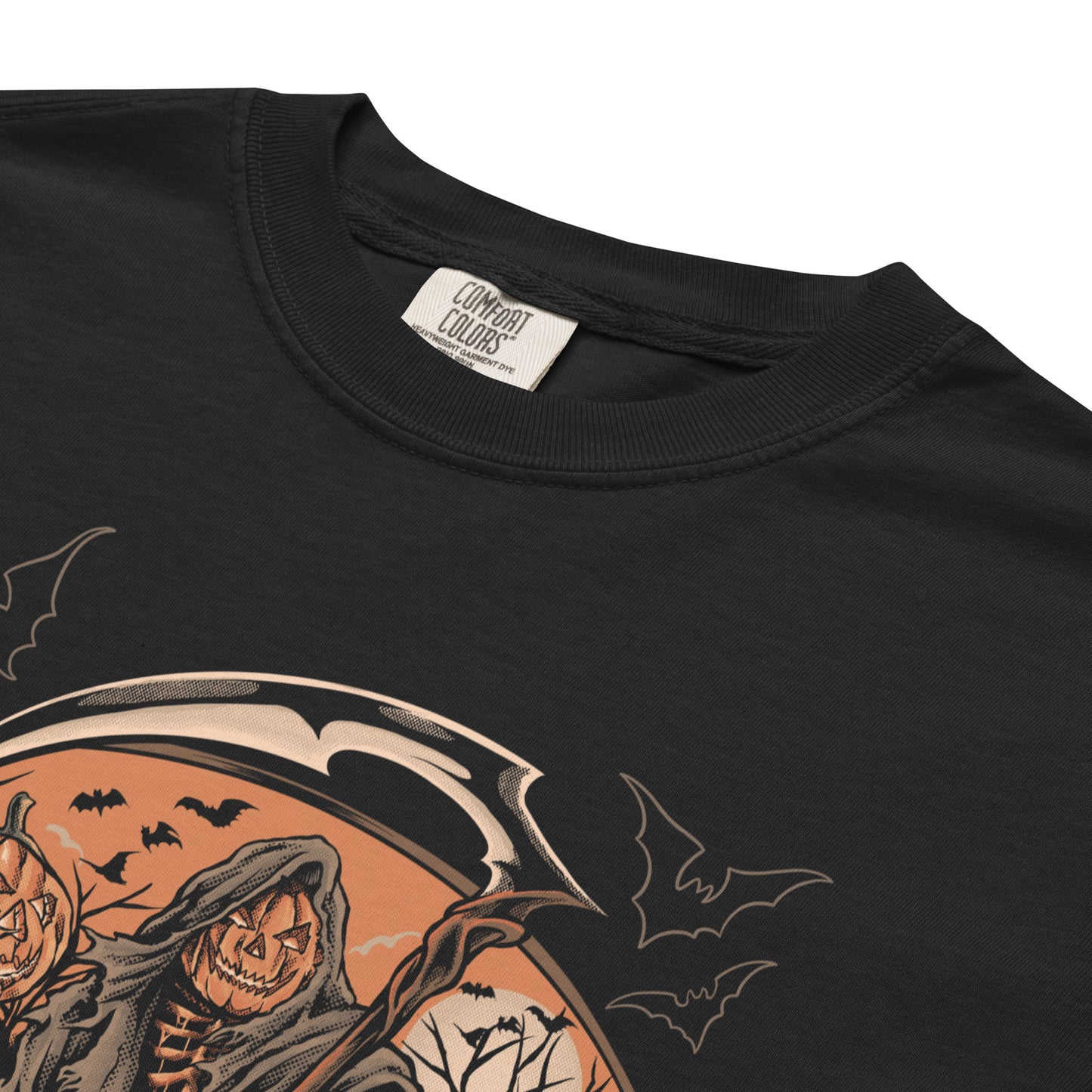 A close up of a black t-shirt with a graphic print of the Grim Reaper among haunted pumpkins, accompanied by a full moon and bats, representing the Halloween theme.
