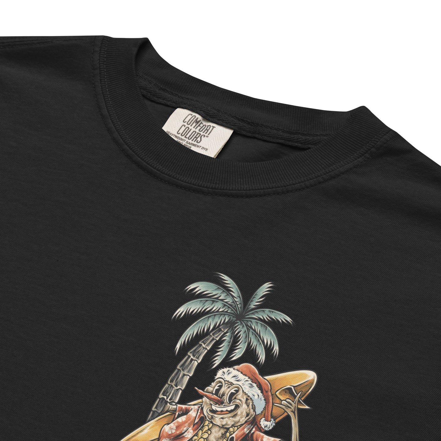 A close up of a black t-shirt with a graphic print of a snowman, palm trees, and beach elements, positioned in front of a stylized depiction of a palm tree.