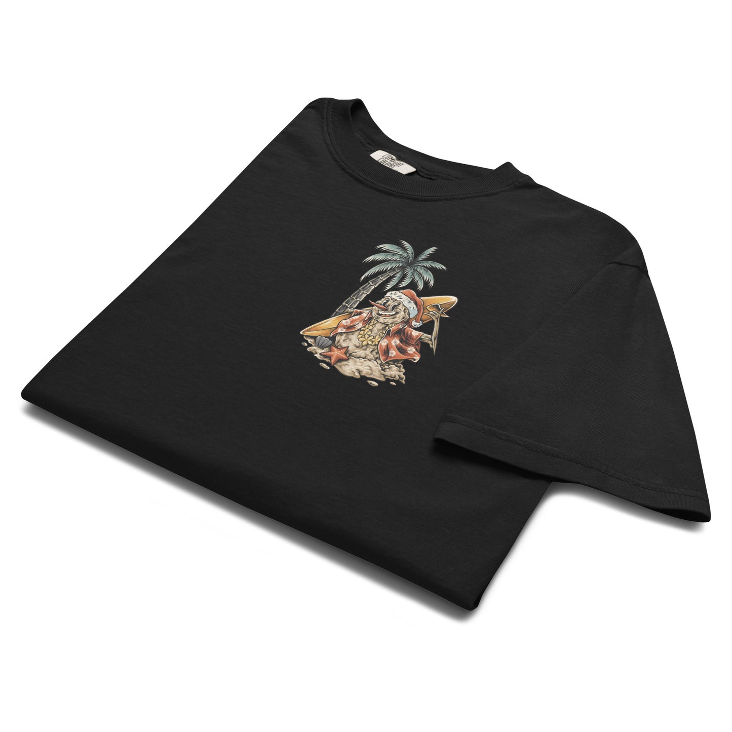 A close up of a folded black t-shirt with a graphic print of a snowman, palm trees, and beach elements, positioned in front of a stylized depiction of a palm tree.