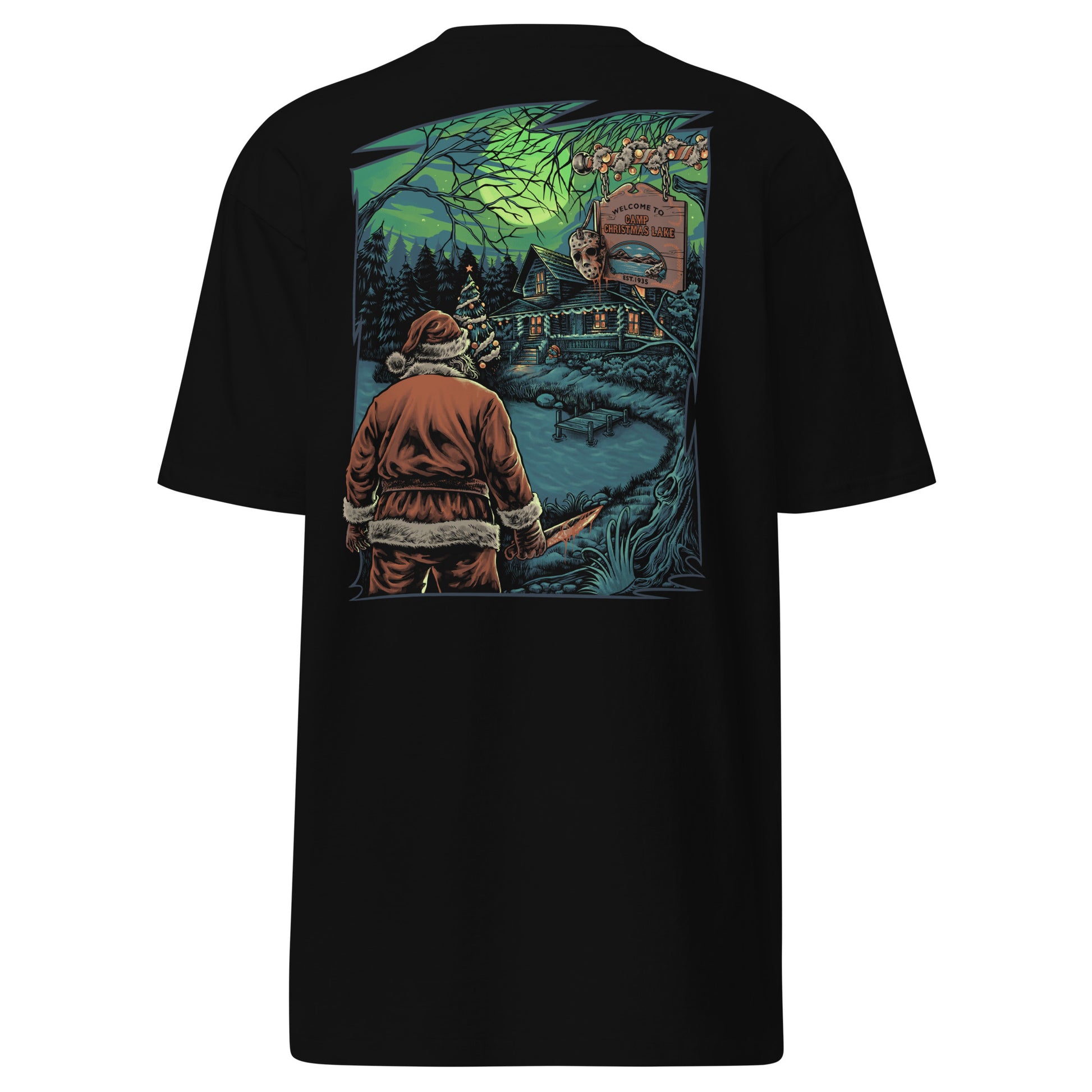 The image shows a black t-shirt with a unique holiday horror print. Santa Claus, axe in hand, stands by a cabin at "Camp Christmas Lake." The scene is illuminated by a full moon with an eerie green glow, reminiscent of classic horror films. This design cleverly merges Christmas iconography with the slasher genre.